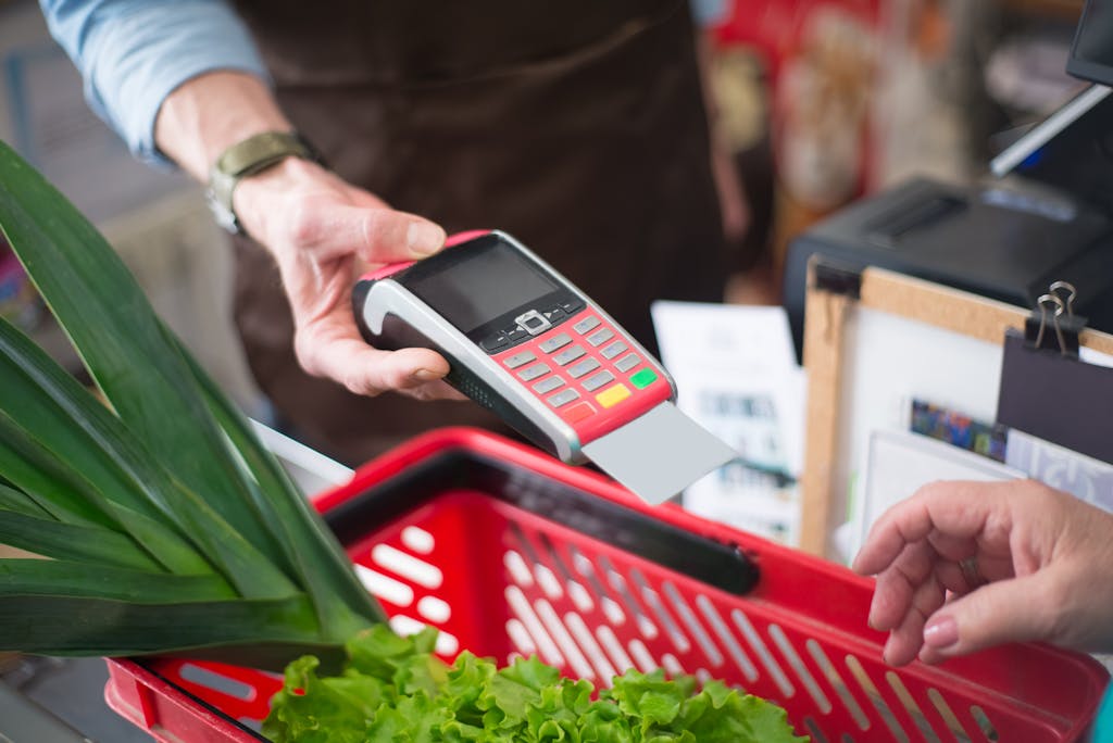 Close-up of a contactless payment at a grocery store with fresh produce in a basket.